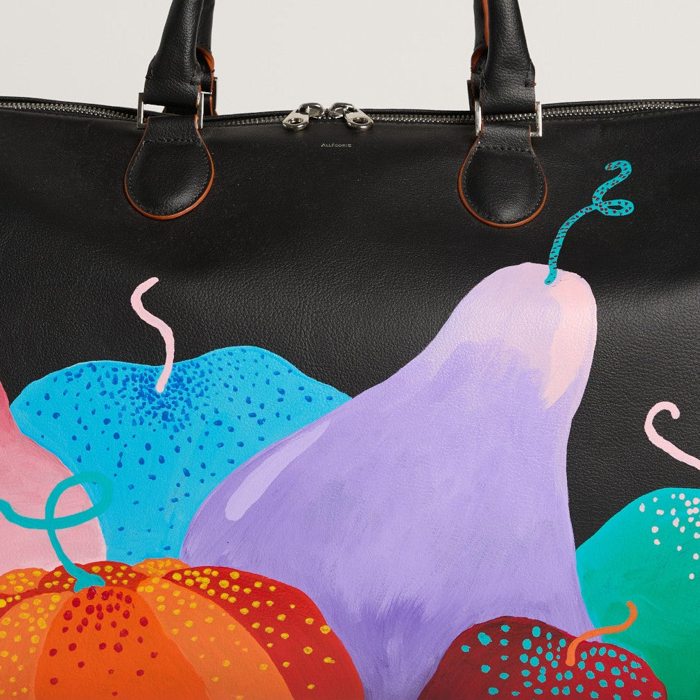 A black vegan apple leather travel bag with a vibrant hand-painted harvest-themed design featuring pumpkins in multiple colors on the exterior.